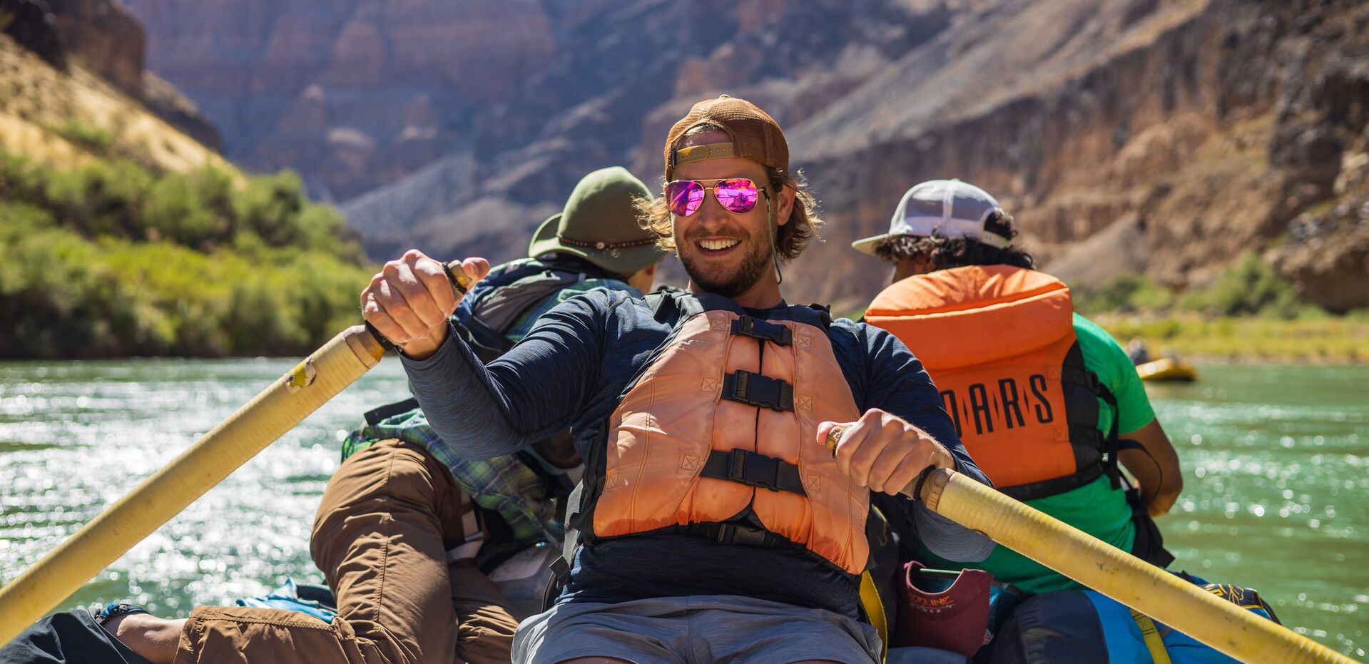 Three people whitewater rafting while wearing lifejackets, paddlesports concept. 