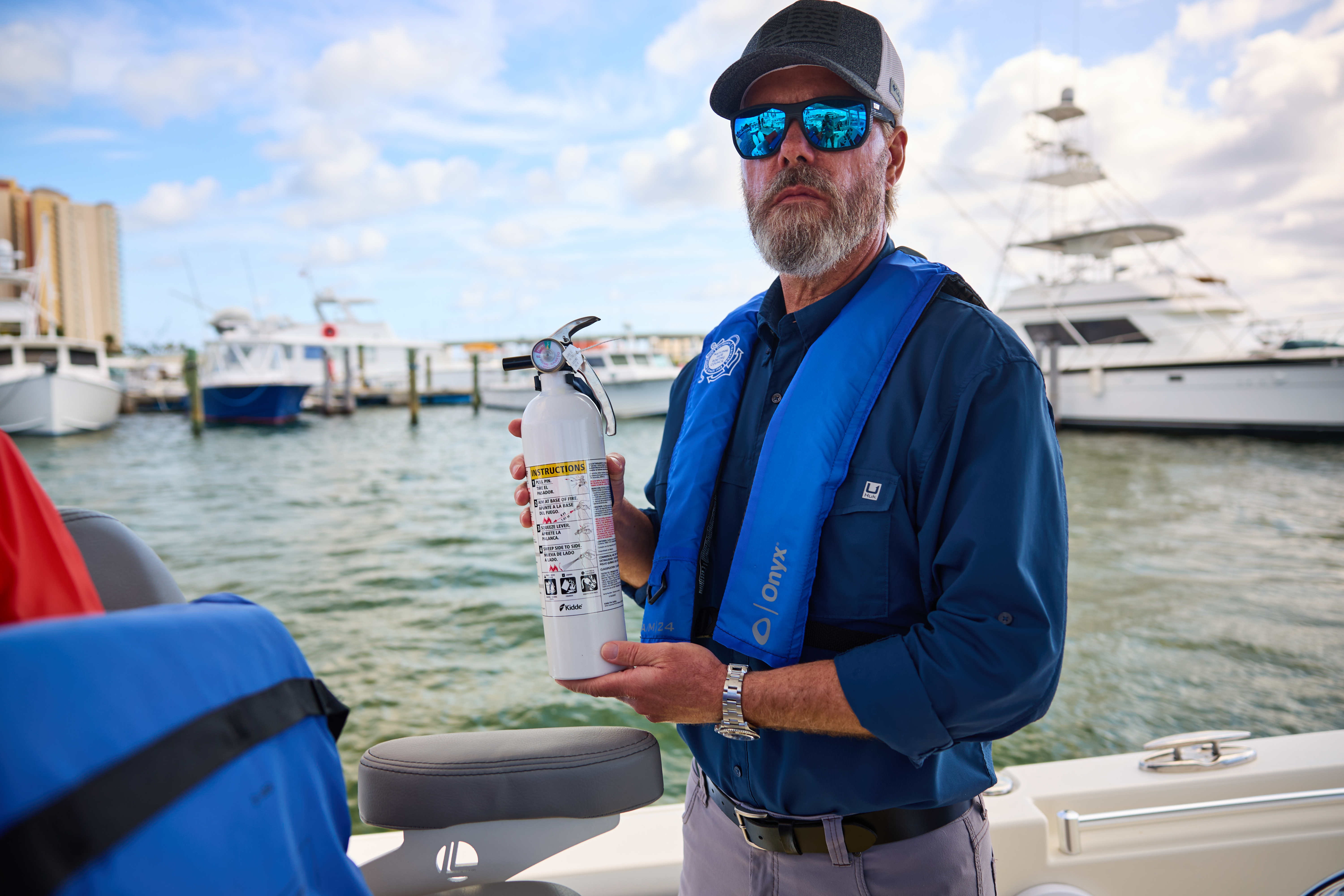 A boater holds a fire extinguisher on a boat. 