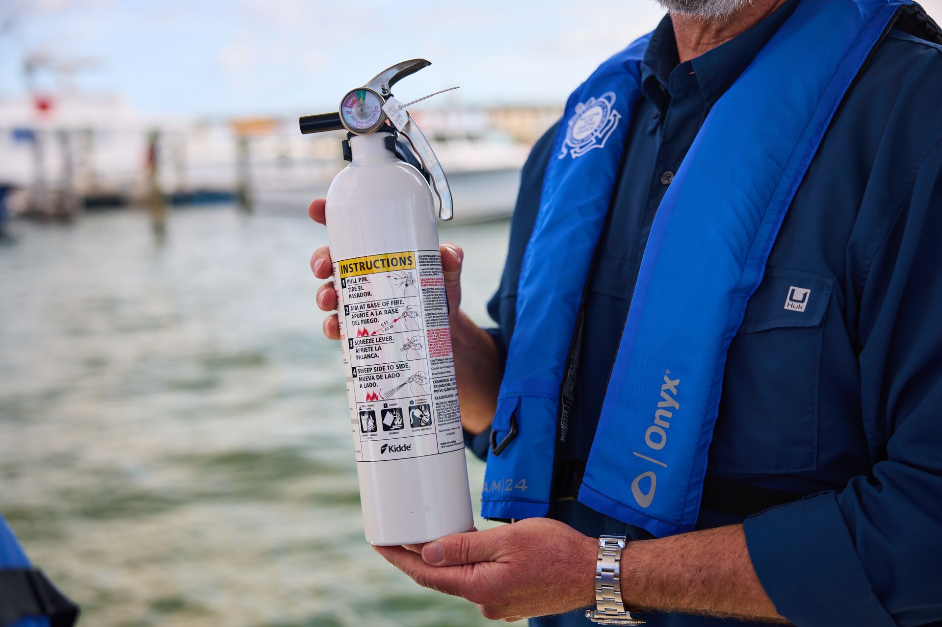 Close-up of a boater holding a fire extinguisher, safety equipment for yachts concept. 