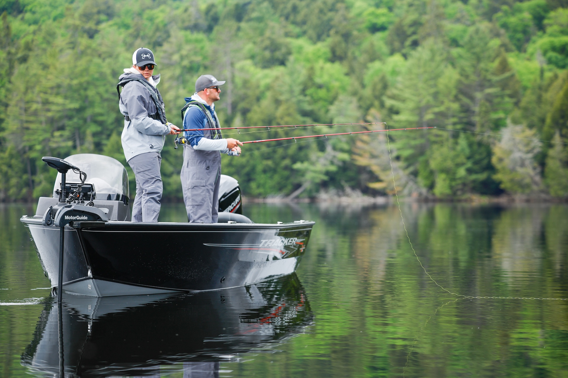 Two people standing in a fishing boat while wearing lifejackets with lines in the water, fishing boat safety concept. 