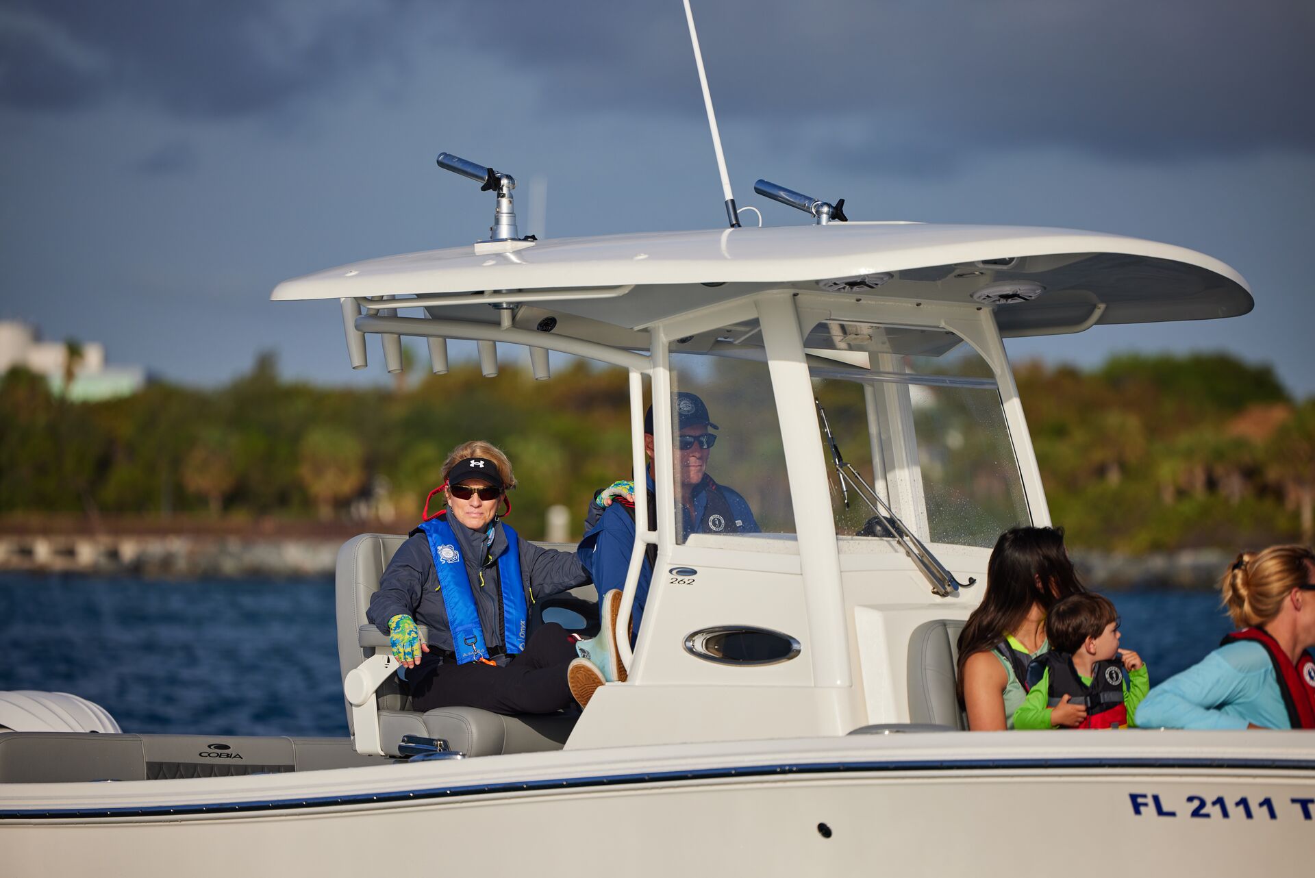 A man and woman drive a boat with other passengers, boat rentals near me concept. 