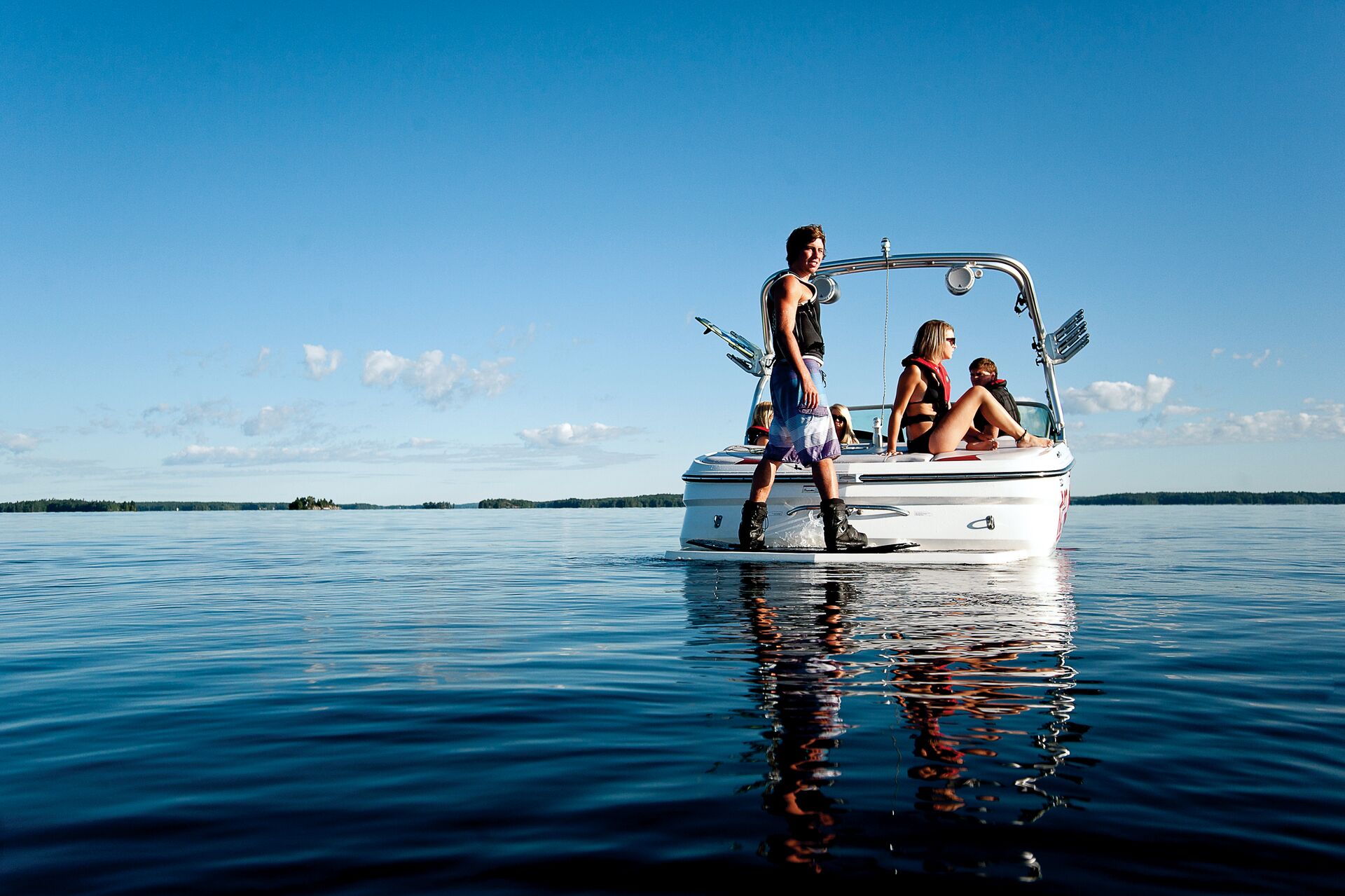 The back of a boat with a man standing on a wakeboard, port vs. starboard concept. 