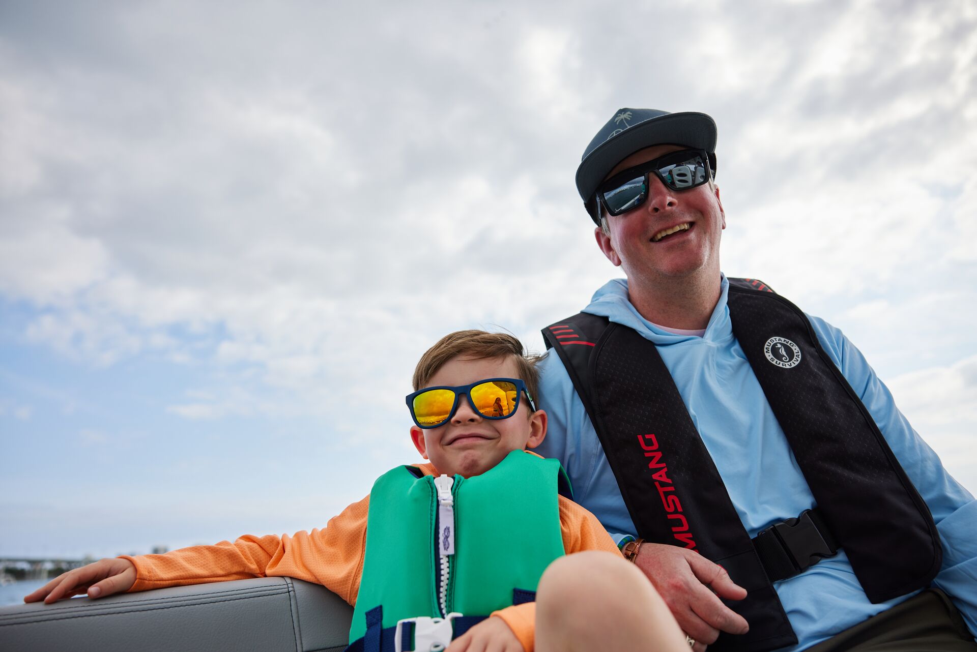 A smiling man and boat wearing life jackets on a boat. 