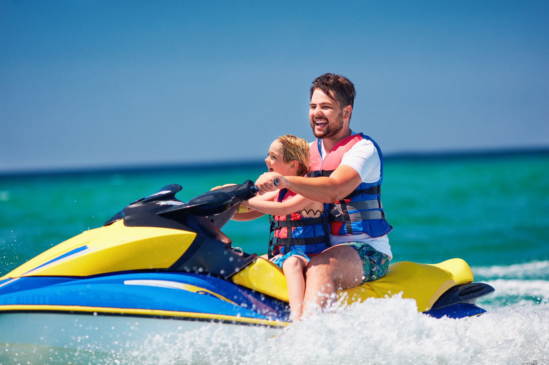 A man and boy on a PWC wearing life jackets, using jet skis safely concept. 