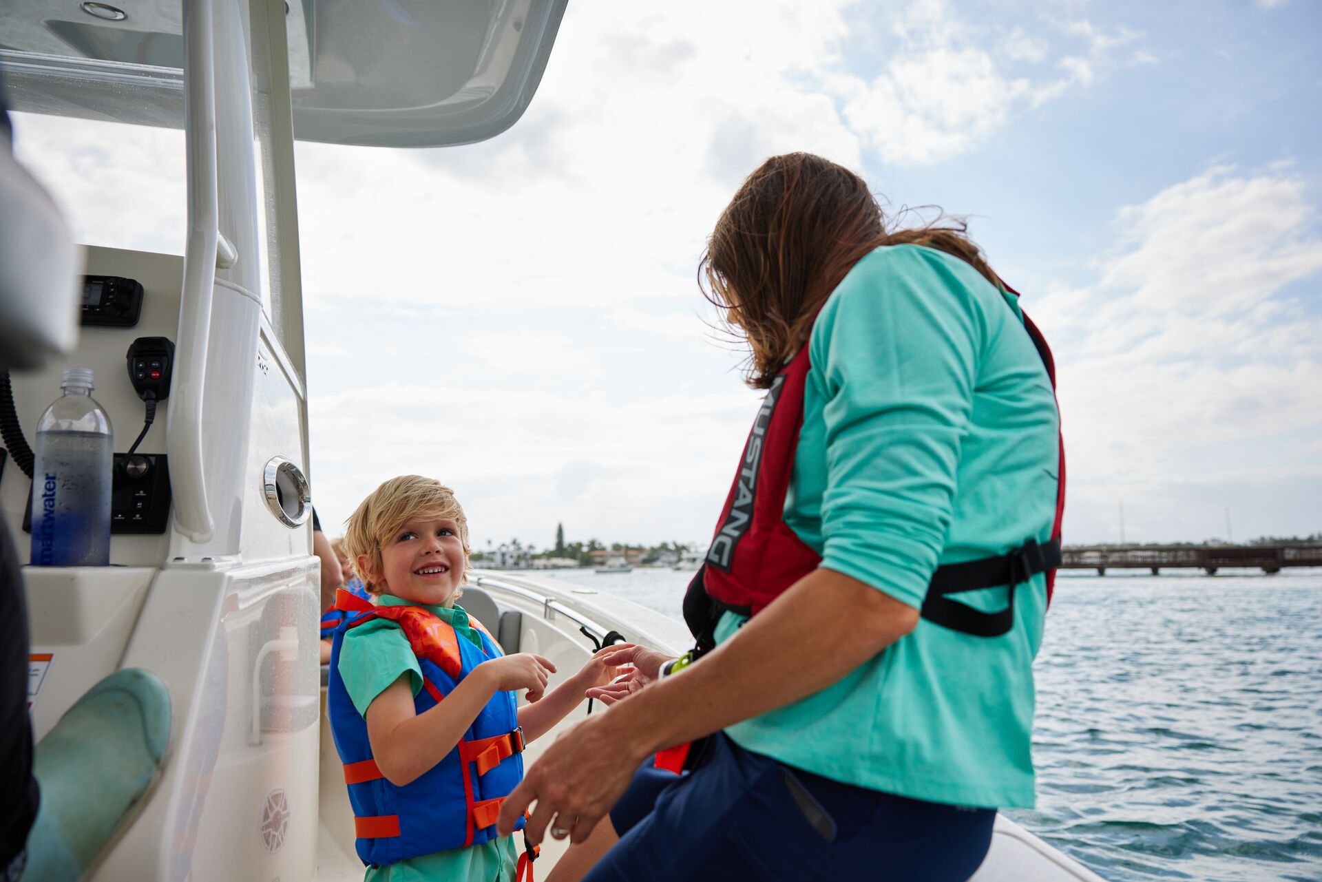 Smiling child with a woman on the side of a boat. 