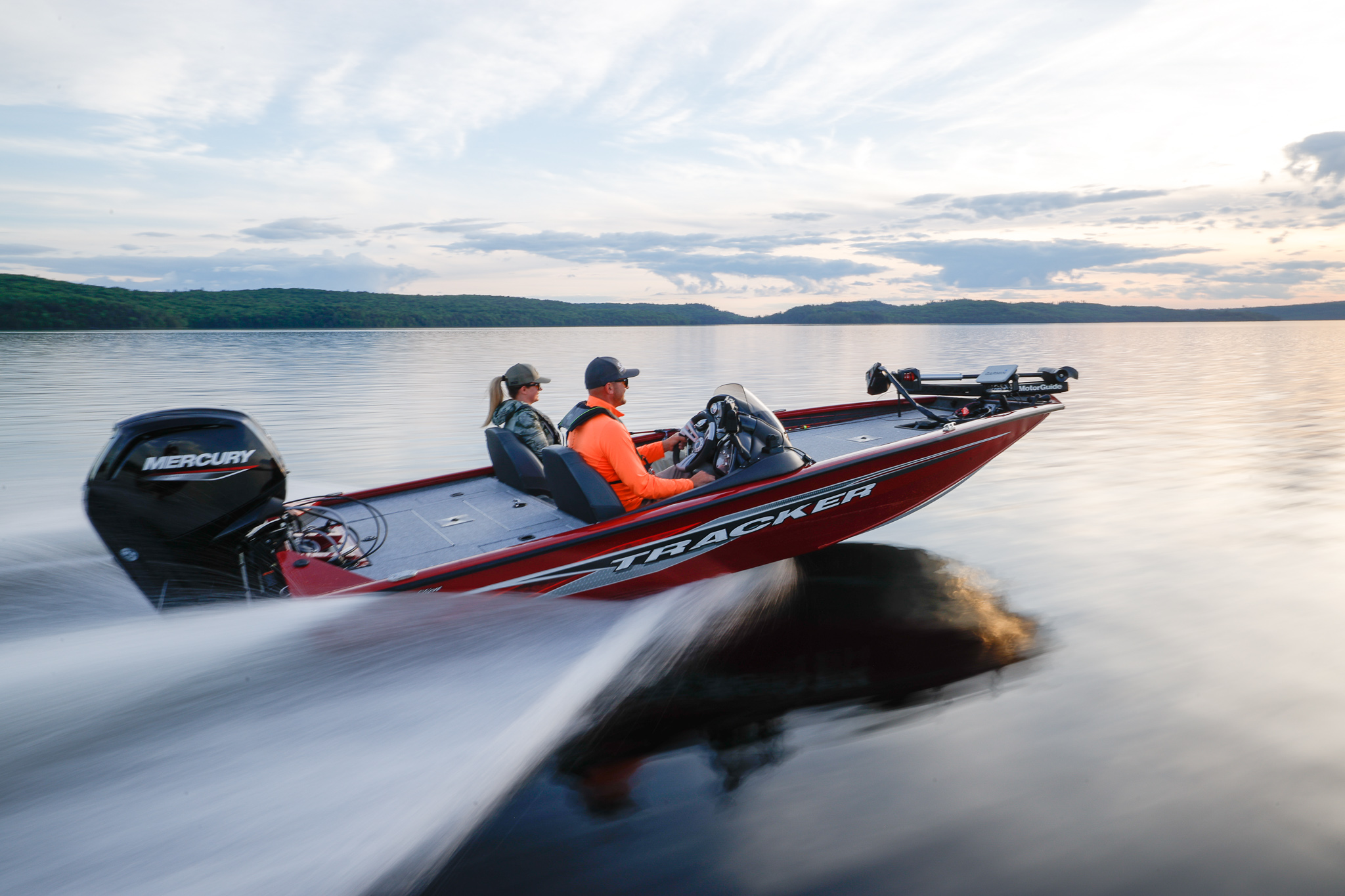 Two people in a bass boat speeding across the water.