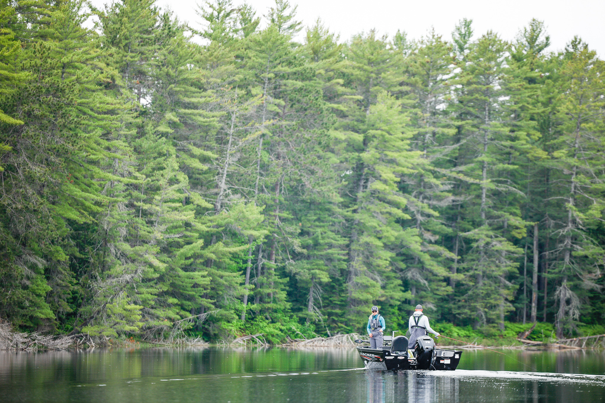 A boat on a lake with two anglers fishing on it. 