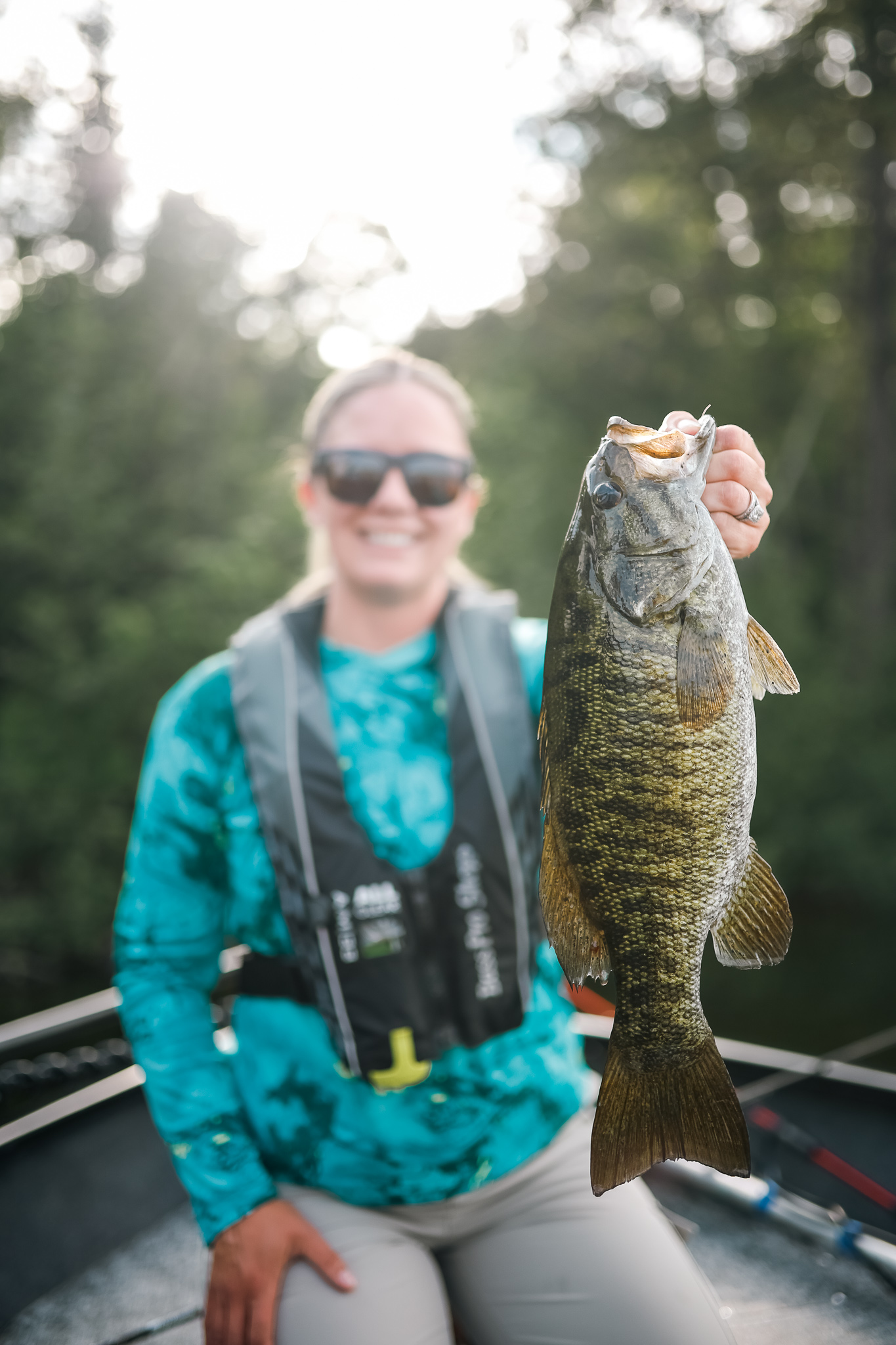 A woman holds a freshly caught bass. 