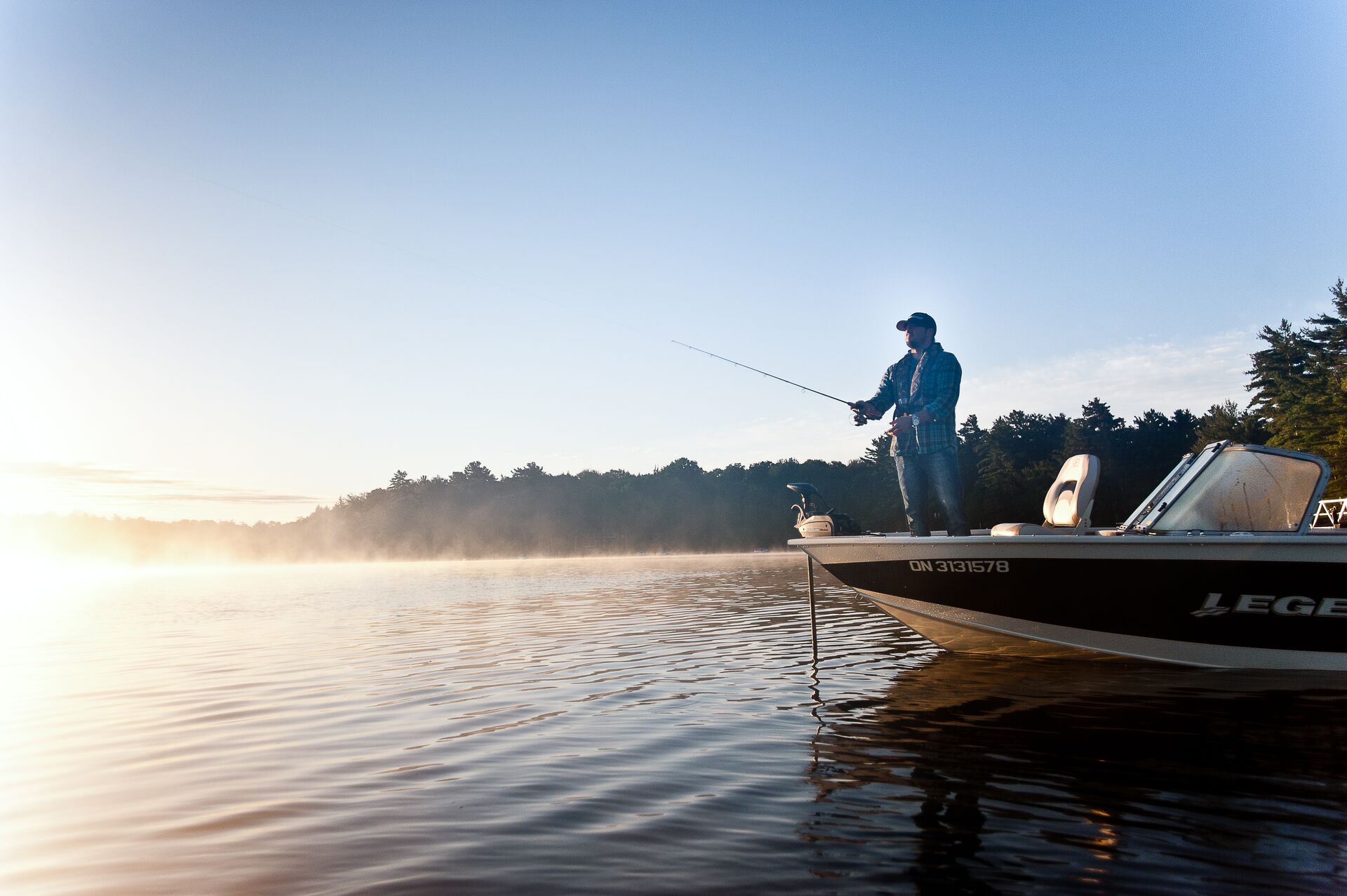 A person fishing from the front of a boat. 