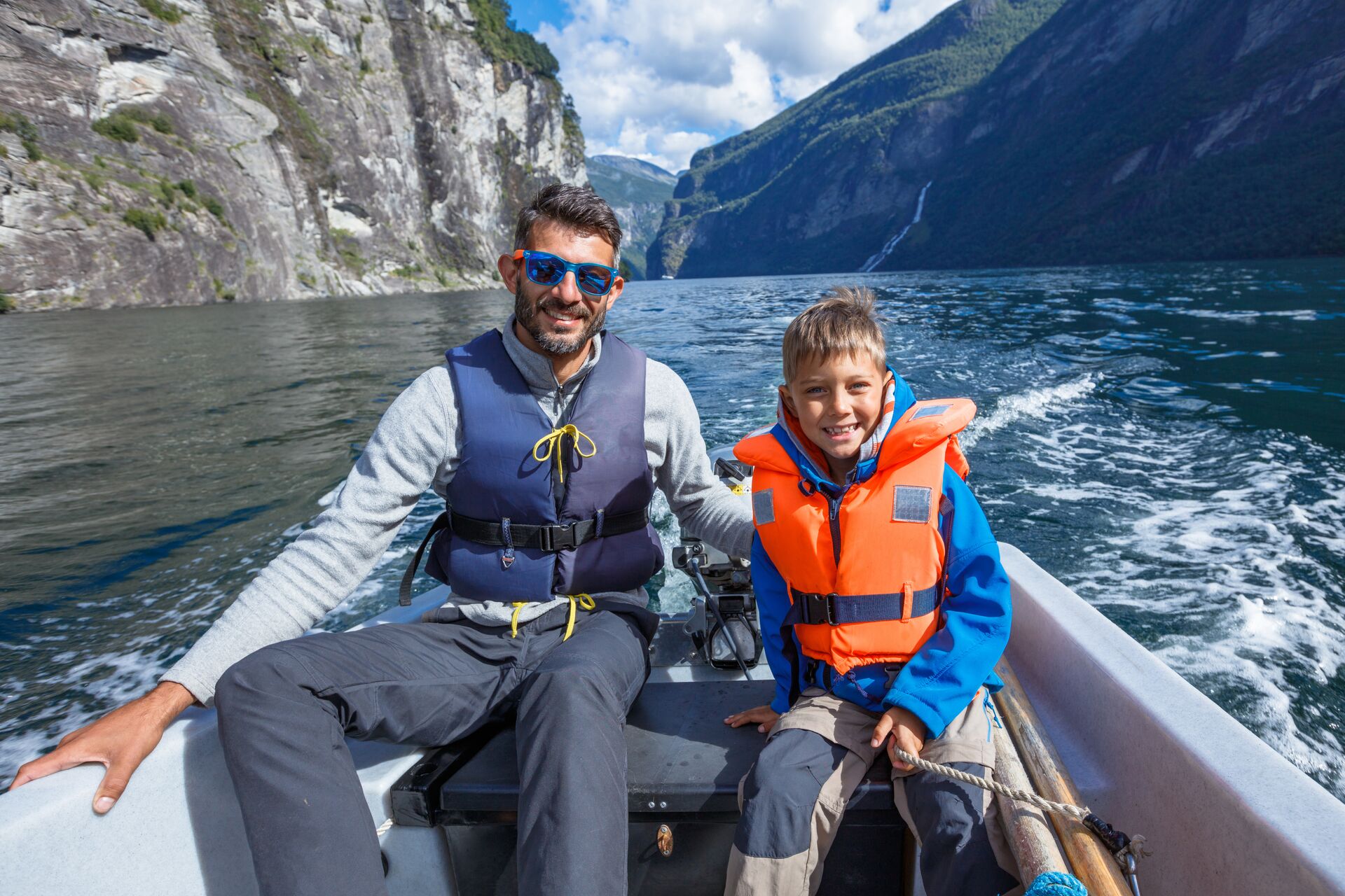 A man and boy wearing warm clothes and life jackets on a small boat, avoid hypothermia concept. 