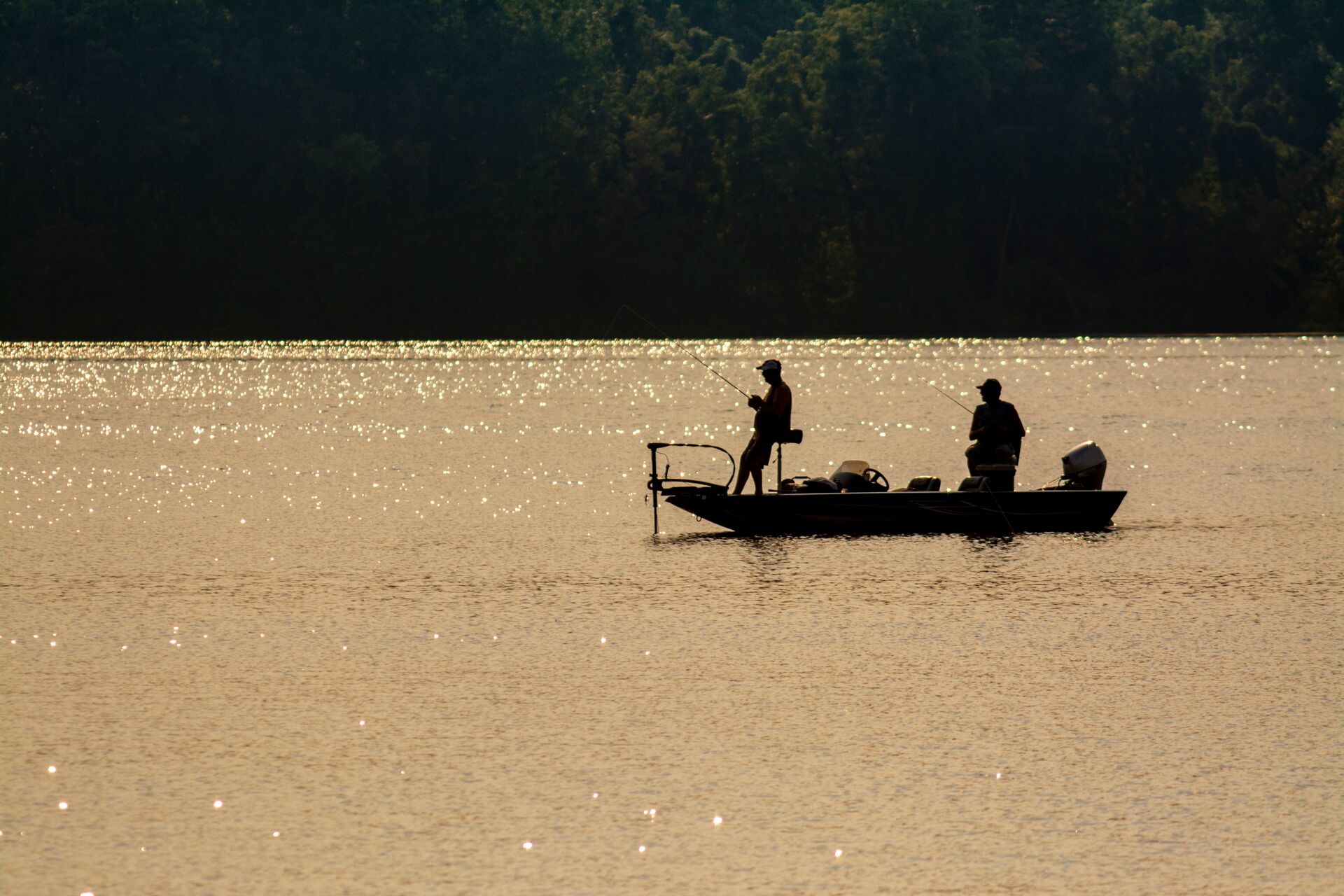 Silhouette of an angler in a boat with a trolling motor. 