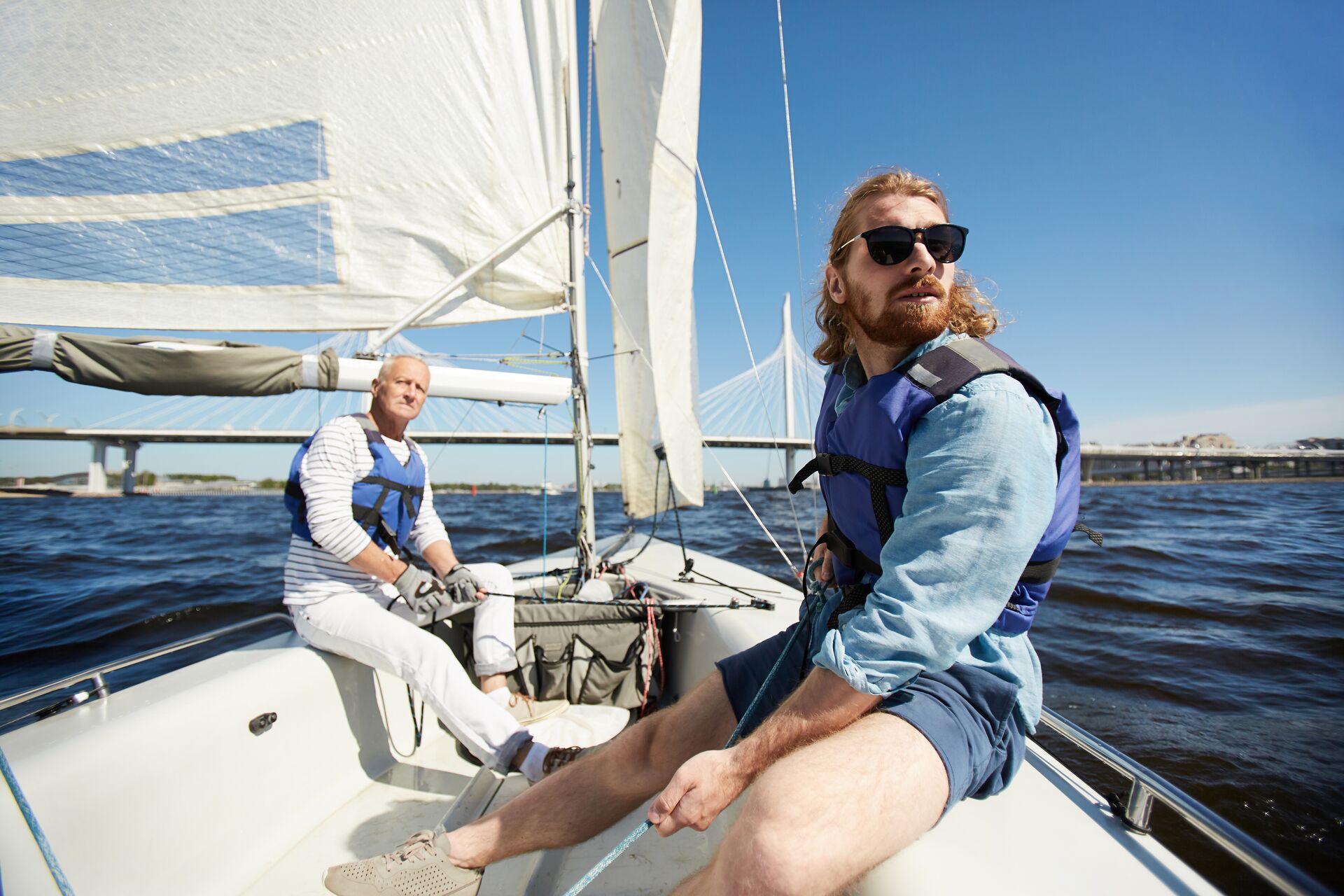 Two men on a sailboat, use a bowline knot for sailing concept. 